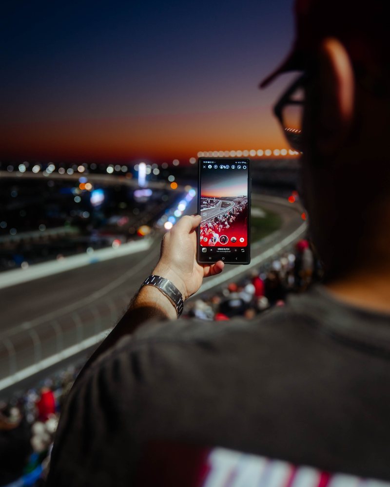 Gast fotografiert mit dem Handy die Rennstrecke bei Sonnenuntergang